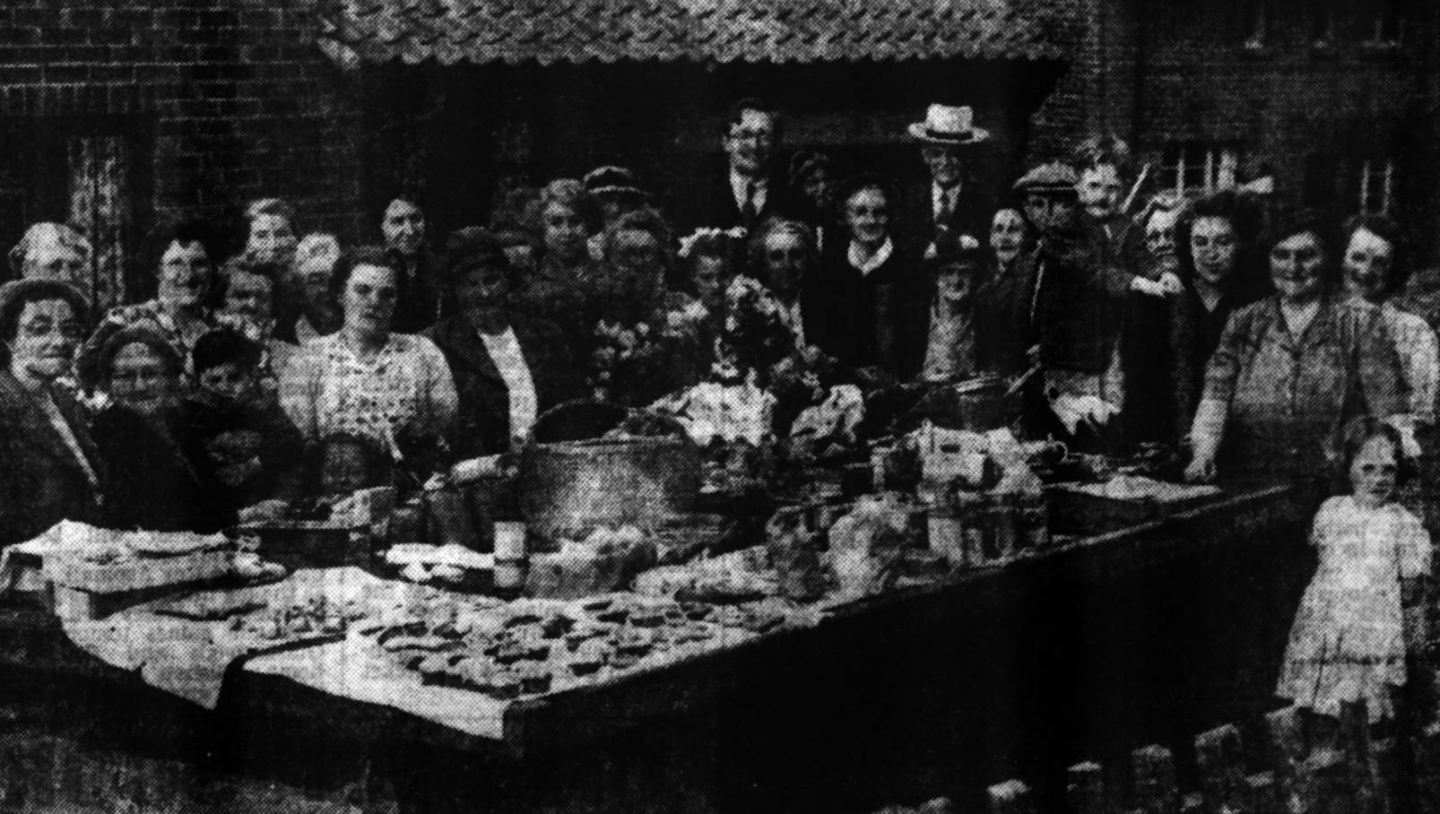 A group of people standing around a table
Description automatically generated